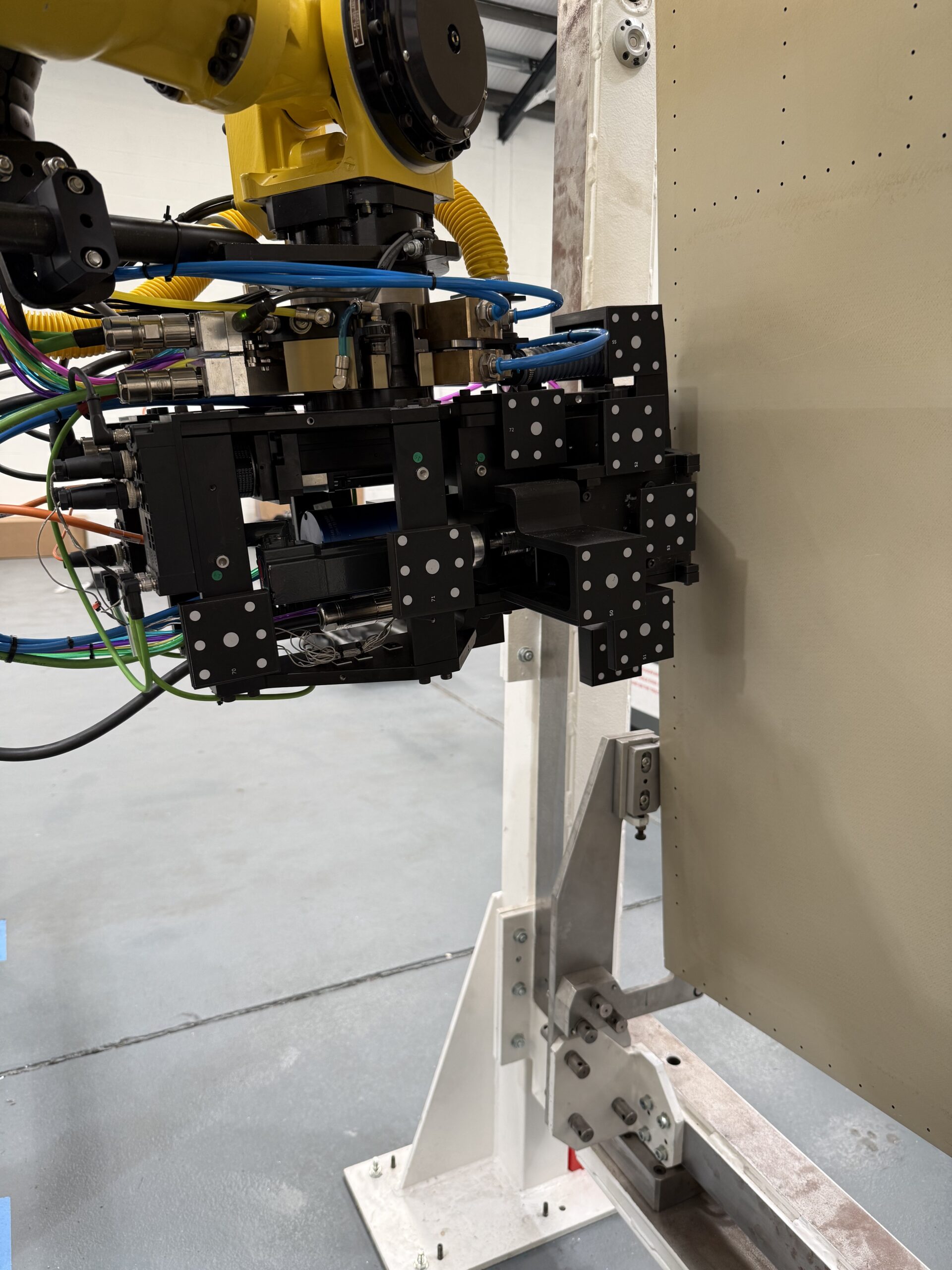 Close-up of TPR robotic drilling tooling positioned against an assembly panel
